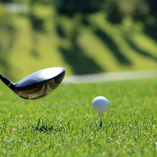 Golfschläger und Golfball im grünen Gras